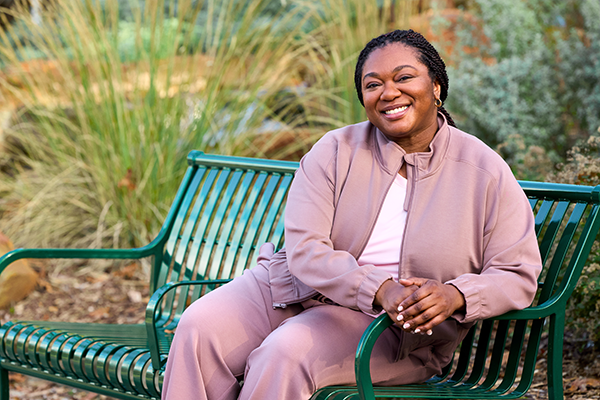 Woman smiling while sitting on park bench.